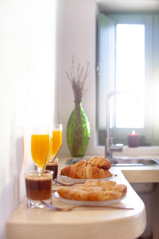 a table with two plates of bread and orange juice at Kapari Suites Santorini in Fira