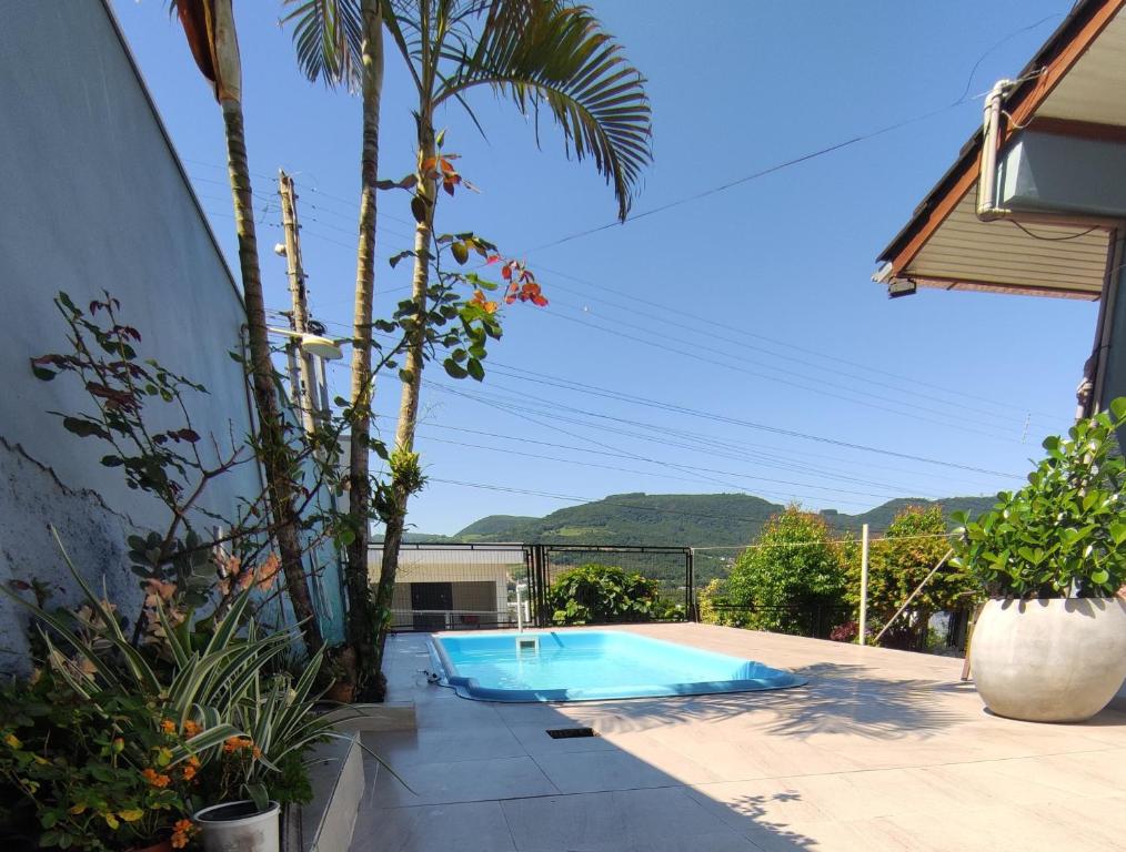 a swimming pool with a palm tree next to a house at Quarto, piscina e acesso exclusivo in Encantado