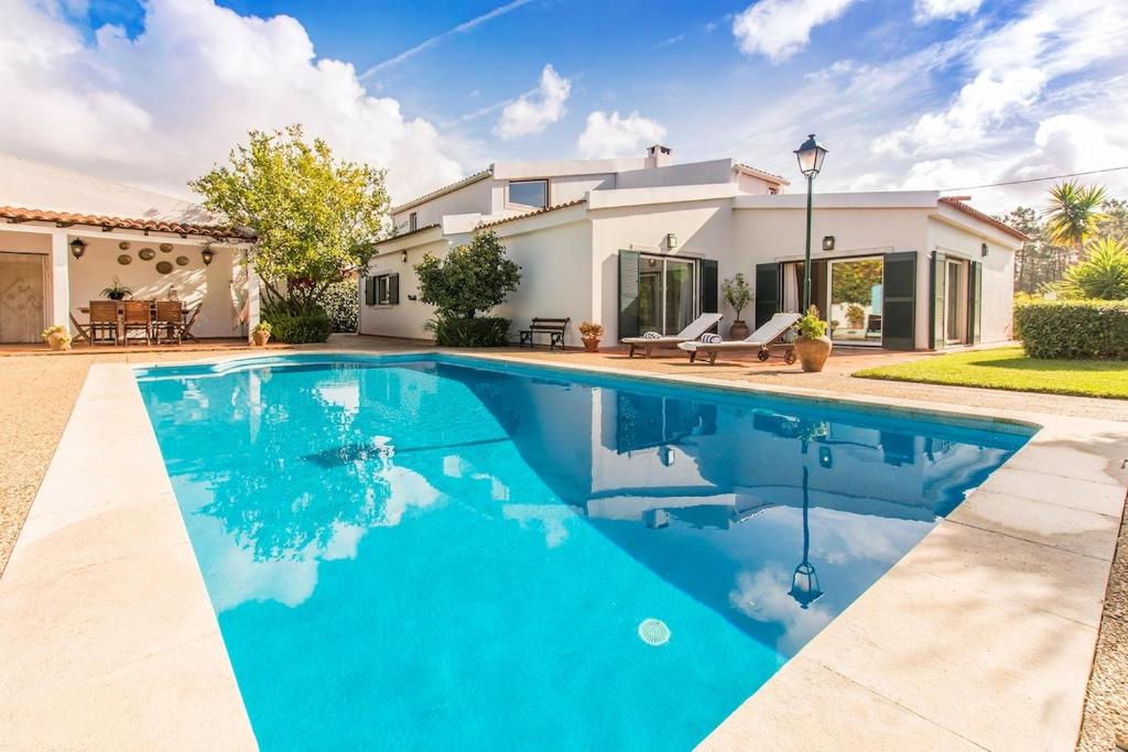 a swimming pool in front of a house at Villa Goreti in Aroeira