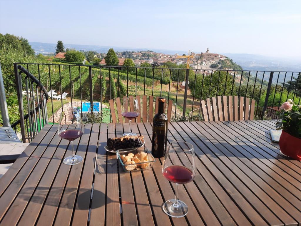 a wooden table with a bottle of wine and wine glasses at Casa Da Cristina Apartment in La Morra