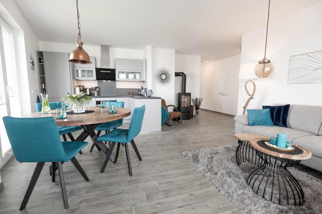 eine Küche und ein Wohnzimmer mit einem Tisch und blauen Stühlen in der Unterkunft Katamaran in Olpenitz