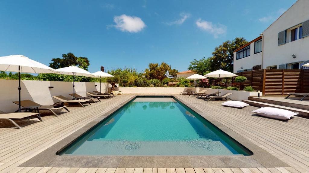 a swimming pool with chairs and umbrellas next to a building at Résidence Villa Branda in Calvi