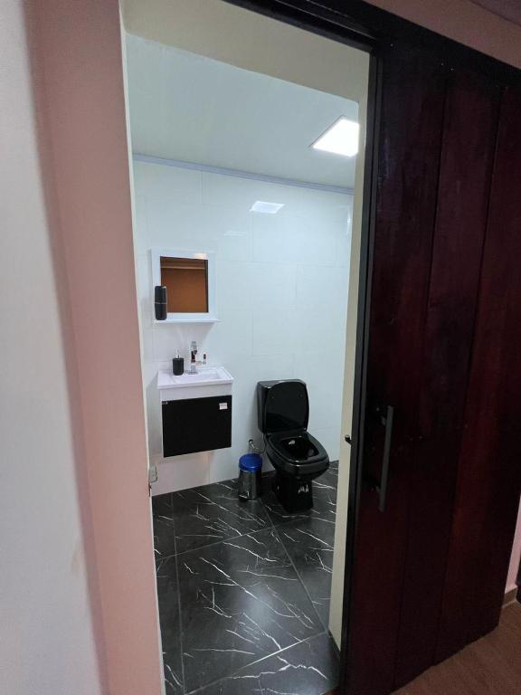 a bathroom with a black toilet and a sink at Container Home Py in Puerto Presidente Franco