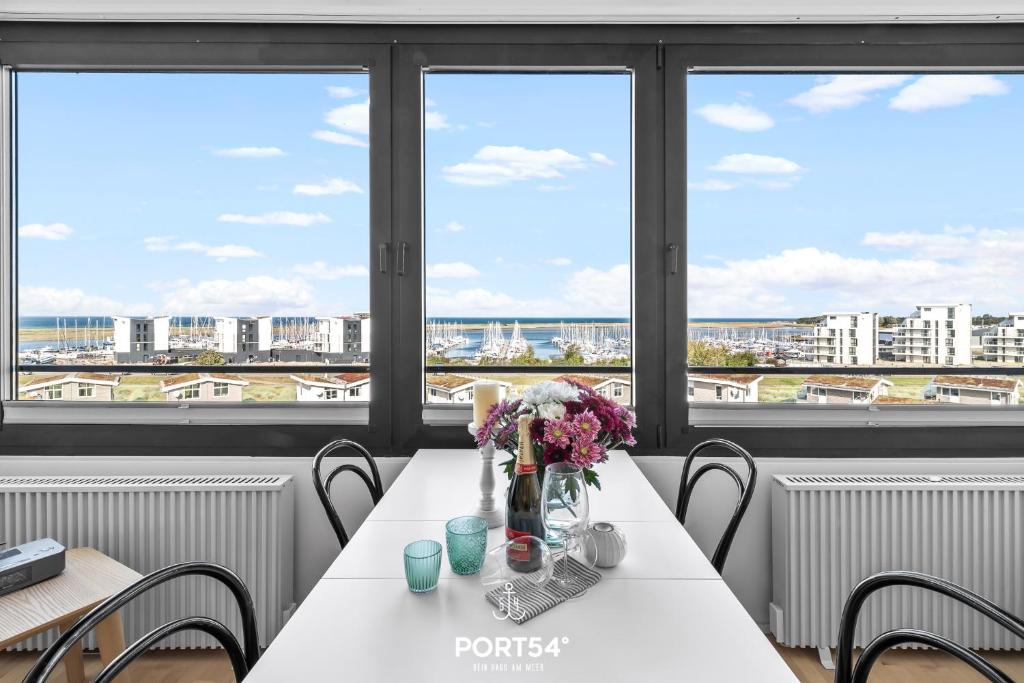 einen Tisch mit Blumen darauf in einem Zimmer mit Fenstern in der Unterkunft Waterfront 7601 Marina Wendtorf in Wendtorf