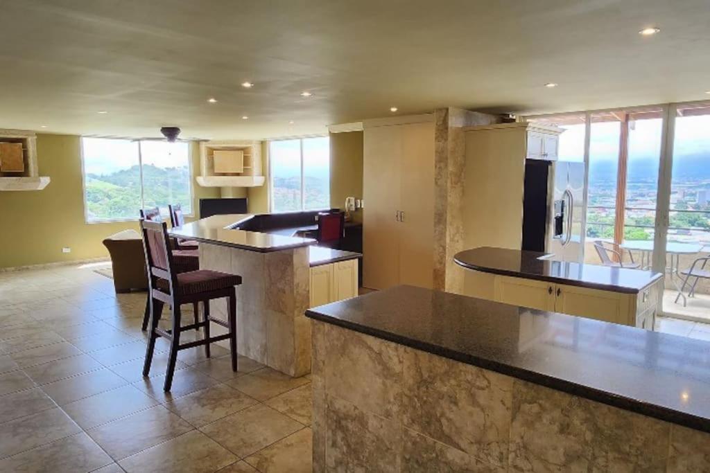 a kitchen with a counter and chairs in a room at Dream Penthouse Escazú in San Rafael