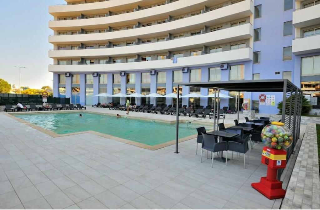 ein großes Gebäude mit einem Pool und Tischen und Stühlen in der Unterkunft Aparthotel Oceano Atlântico 1 in Portimão