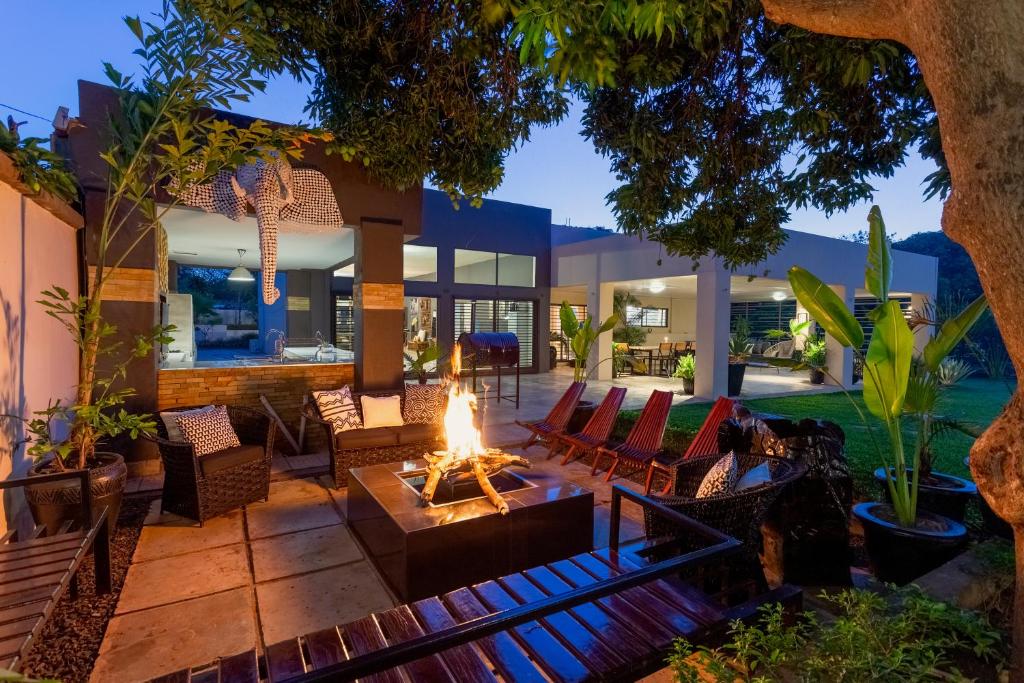 sala de estar al aire libre con hoguera y patio en La Caduta Luxury Villa, en Livingstone