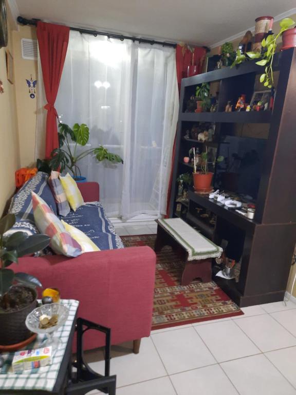 een woonkamer met een rode bank en een tafel bij Comparto Depto. en La Cisterna ( hermoso y cómodo, cómo en casa) in Santiago