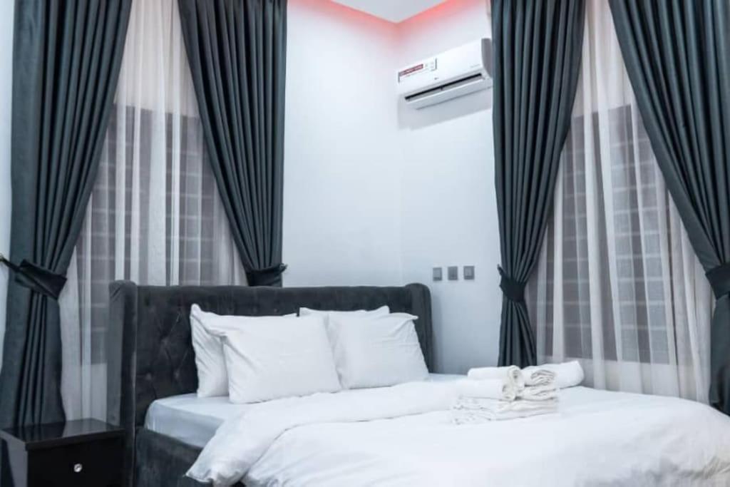 1 dormitorio con 2 camas y cortinas blancas y negras en Alnavi Homes ShortStay Apartment, en Abuja