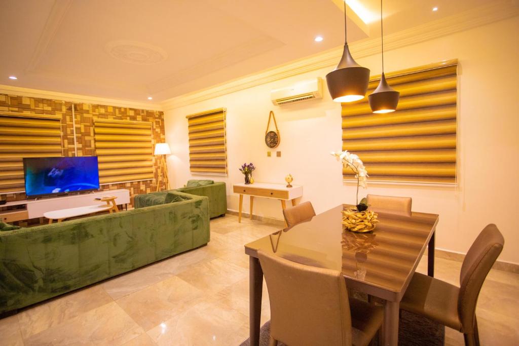 een woonkamer met een tafel en een groene bank bij Luxury 3 bed Apartmnt with Minimalist Aesthetic in Abuja