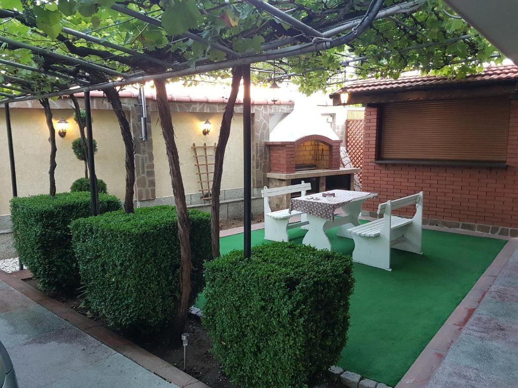 um pátio com uma mesa e bancos num piso verde em Къща за гости Жорж em Bankya