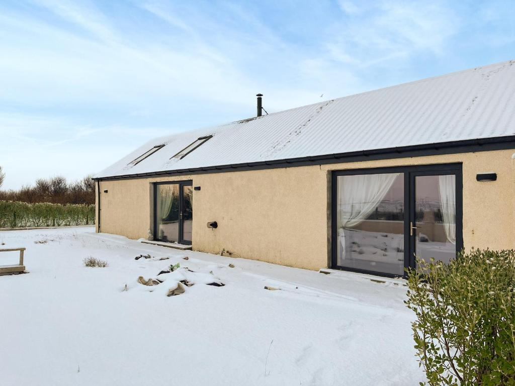 una casa en la nieve con techo en Bayview Byre, en Knock