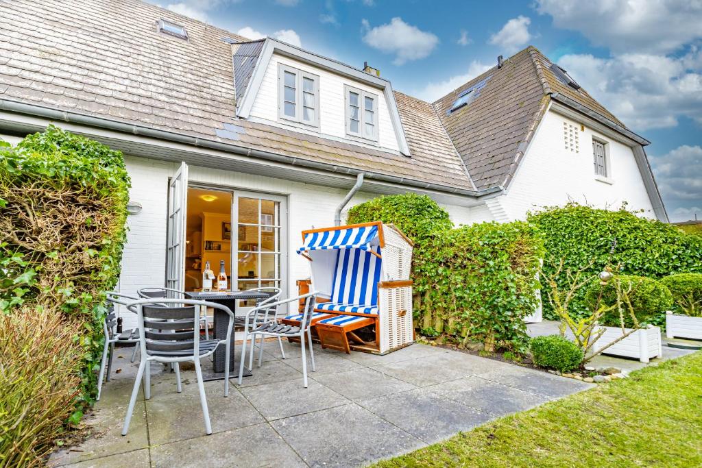 a patio with chairs and a table in front of a house at Westerhörn 46 15 in Keitum