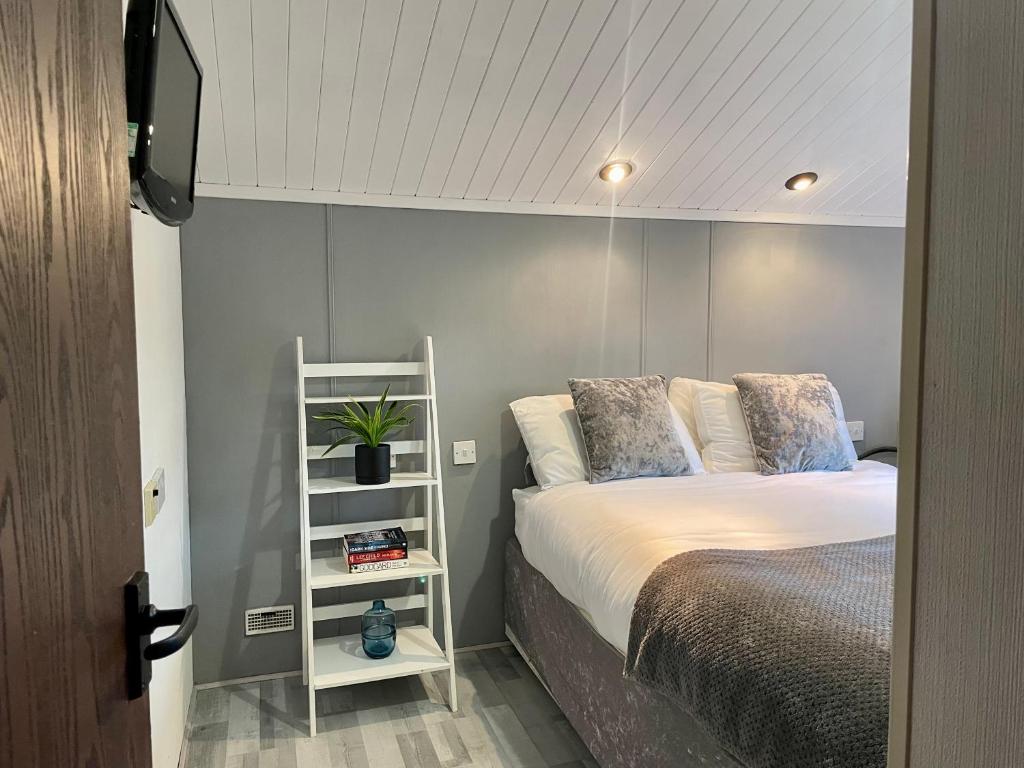 a bedroom with a bed and a white shelf at Cosy 3 Bed Lodge in Hoburne, Cotswolds in South Cerney