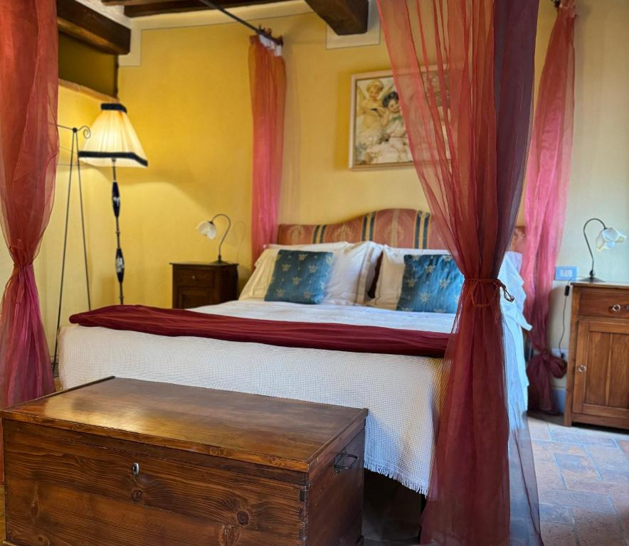Schlafzimmer mit einem Bett mit roten Vorhängen in der Unterkunft Pienzalettings "Suites" in Pienza