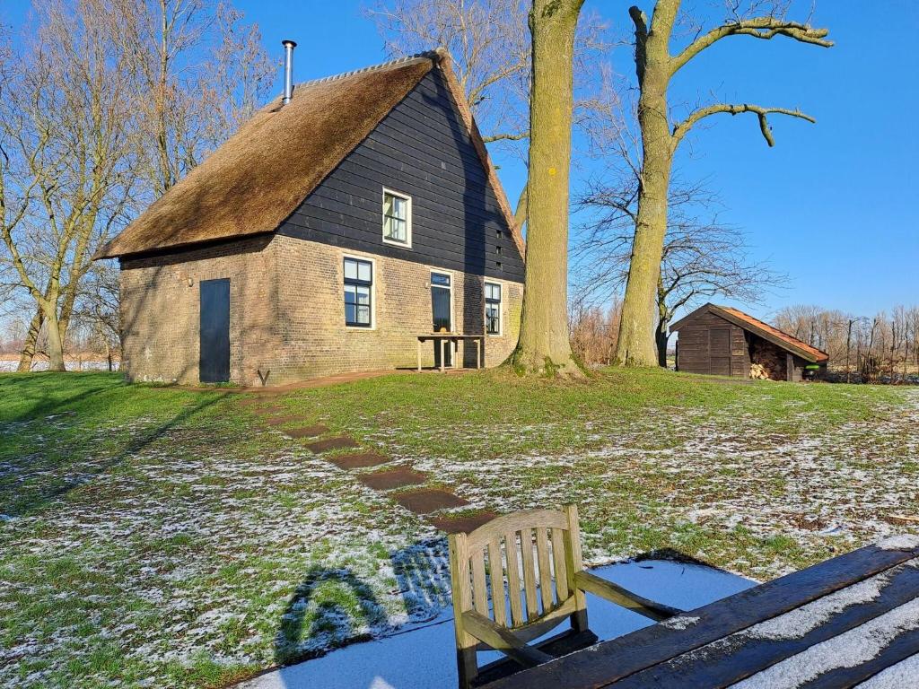 un banco frente a un edificio con un árbol en Picturesque Holiday Home in Drimmelen with Garden, en Hooge Zwaluwe