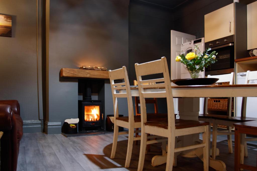 a kitchen with a table and chairs and a fireplace at Black Pearl Apartment New Brighton in Wallasey