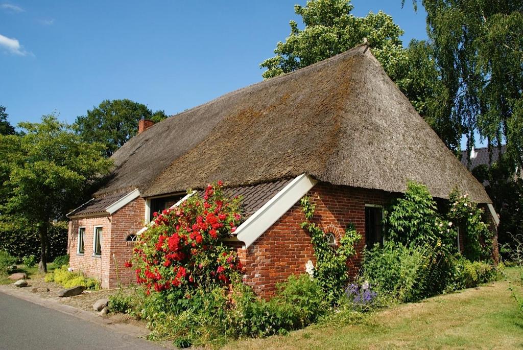 een klein bakstenen huis met een rieten dak met bloemen bij De Leemstee, Authentieke boerderij met modern comfort in Eext