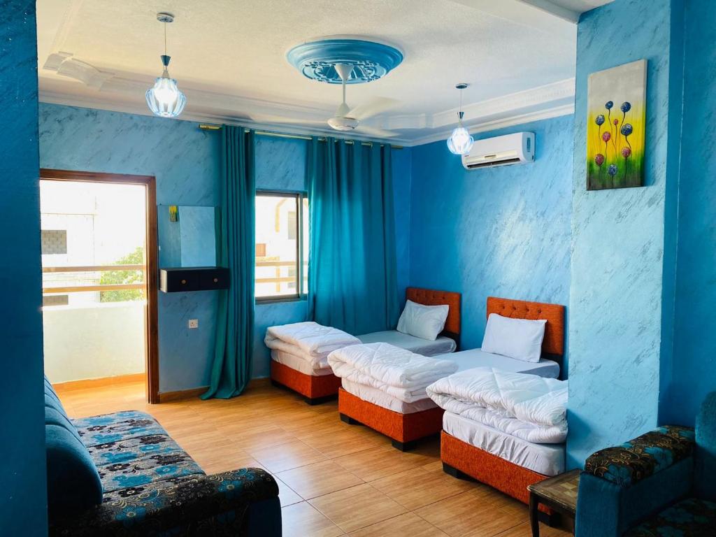 a blue room with two beds and a couch at Galaxy Apartments in Aqaba