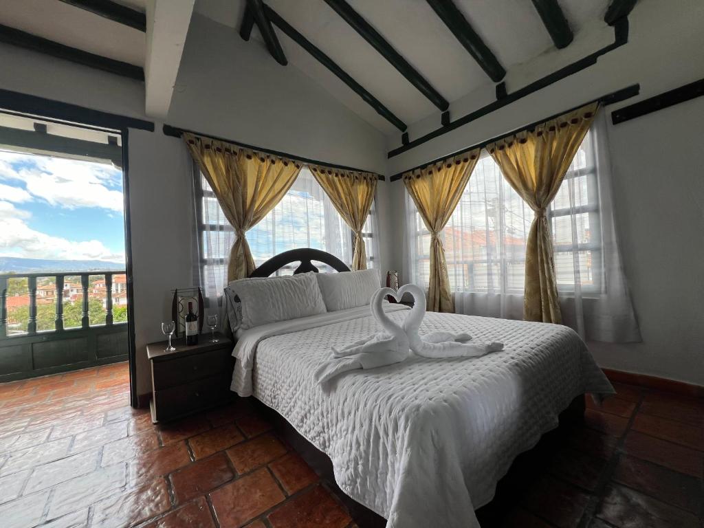 um quarto com uma cama com lençóis brancos e janelas em CASA VILLA LUGUIANGA Villa de Leyva em Villa de Leyva