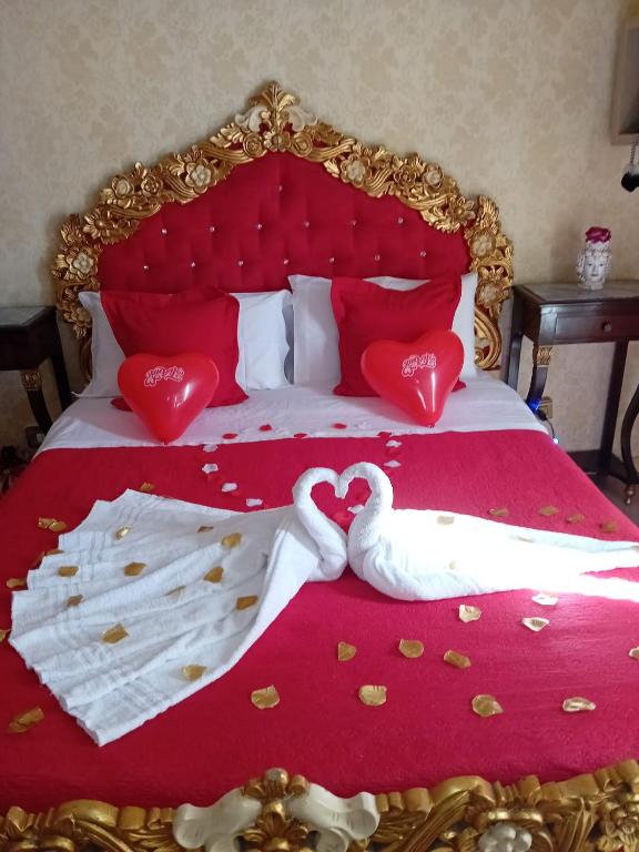two swans are laying on a bed with hearts at B&B Sotto gli archi in Catania