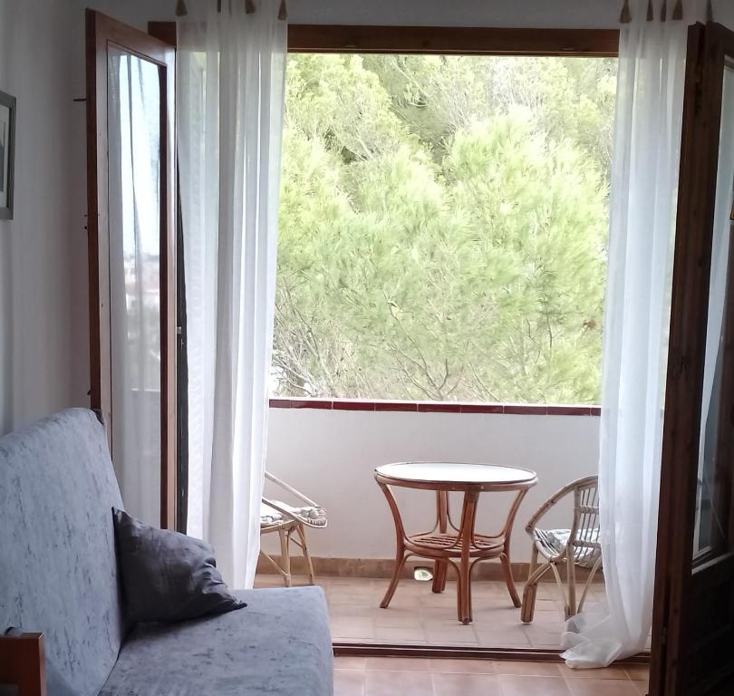 Una sala de estar con una mesa y una gran ventana. en Sol Isla, en Arenal d'en Castell