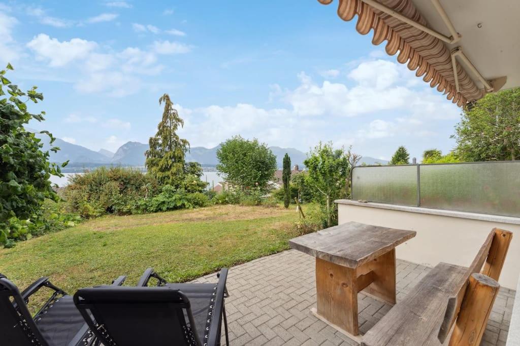 einen Holztisch und Stühle auf einer Terrasse mit Aussicht in der Unterkunft Lakeview apartment in beautiful Oberhofen in Oberhofen am Thunersee