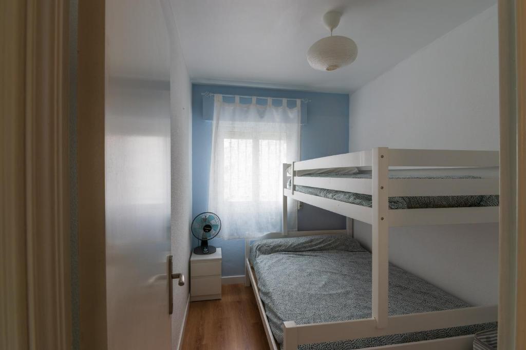 Cosy 2BR flat in Nuevo Portil city centre في إل بورتيل: غرفة نوم صغيرة مع سرير بطابقين ونافذة