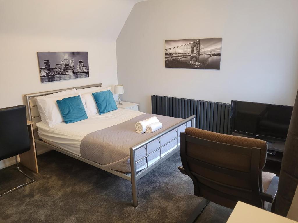 a bedroom with a bed with blue pillows and a desk at Roomstay Hemel in Hemel Hempstead