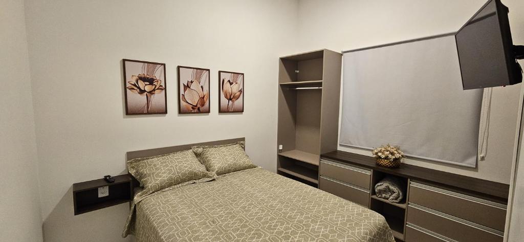 a bedroom with a bed and some pictures on the wall at Flat na Av. Fernando Côrrea in Cuiabá