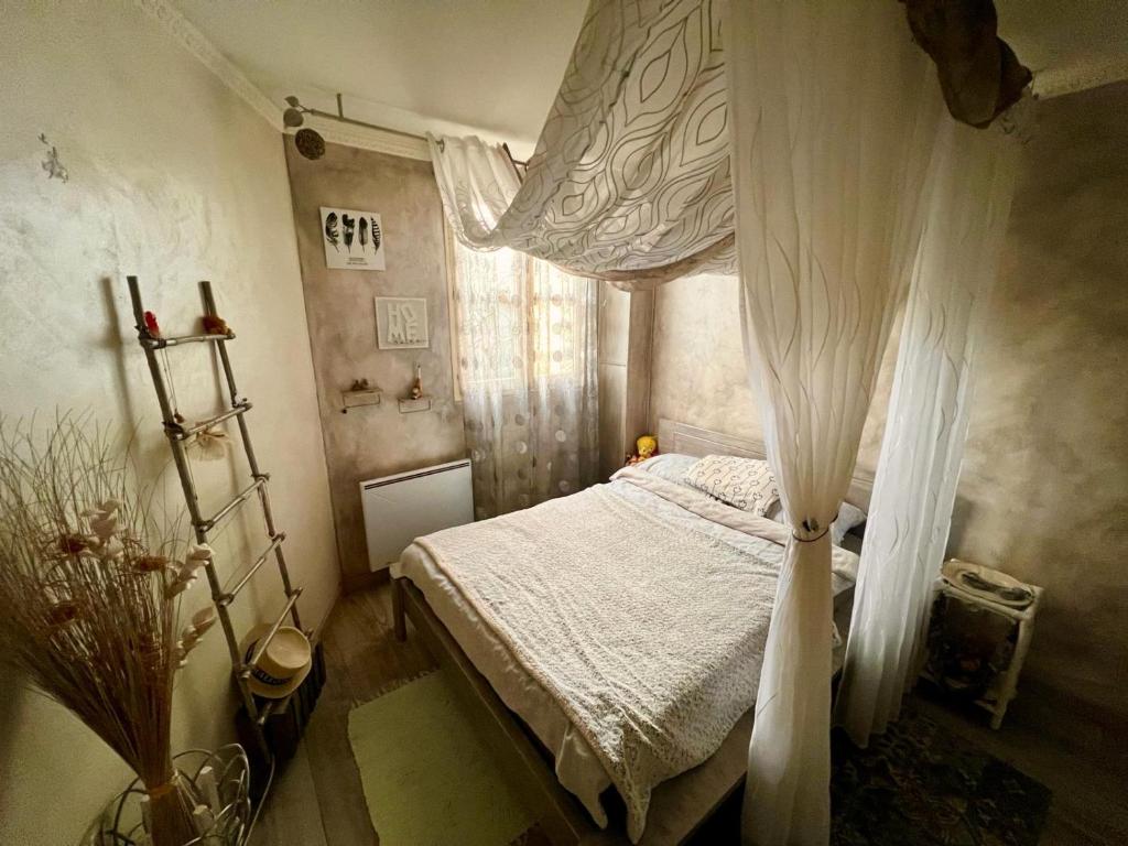 1 dormitorio con cama con dosel y cortinas blancas en les clés de jonzac-conciergerie, les jardins de Boussy en Boussy-Saint-Antoine