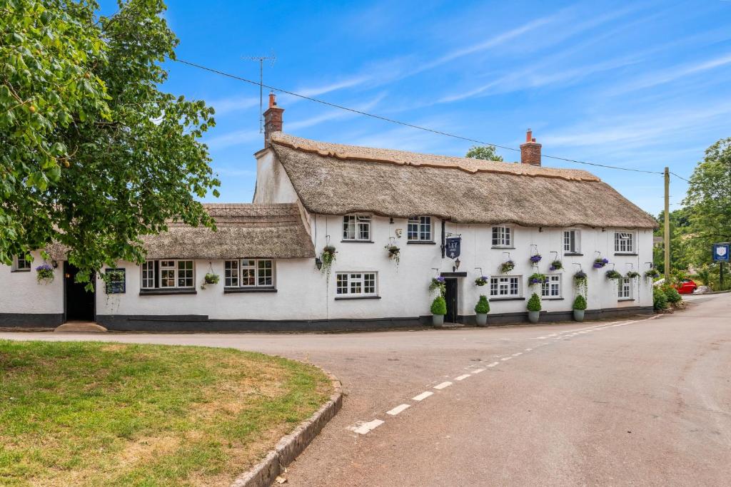 an old white cottage with a thatched roof at The Ley Arms in Exeter