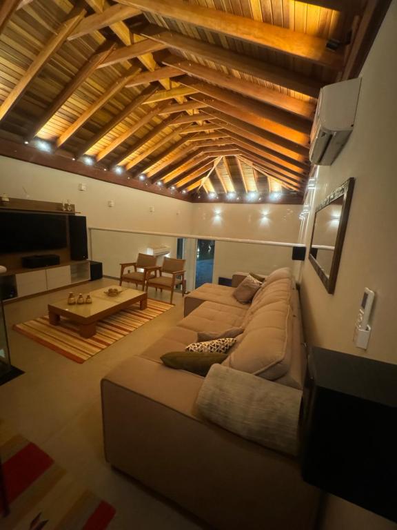a living room with a large couch and a television at Locação Terras de São Francisco, Quarto Flamboyant in Andradas