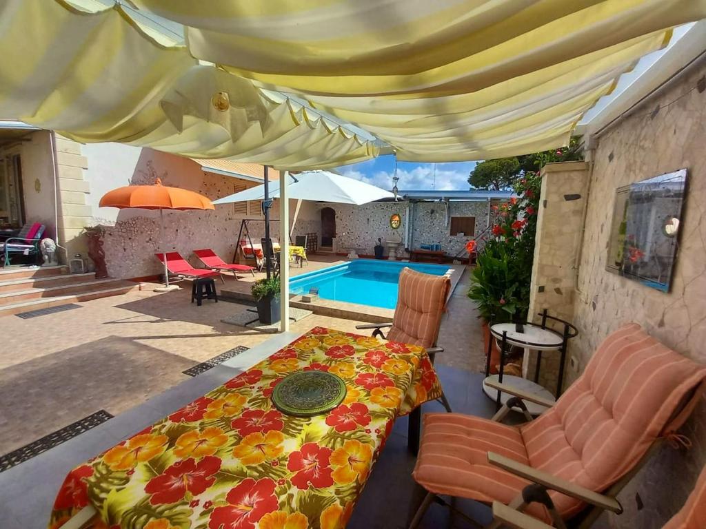 um pátio com uma mesa e cadeiras e uma piscina em 2 bedrooms property with shared pool at Porto Cesareo 1 km away from the beach em Porto Cesareo