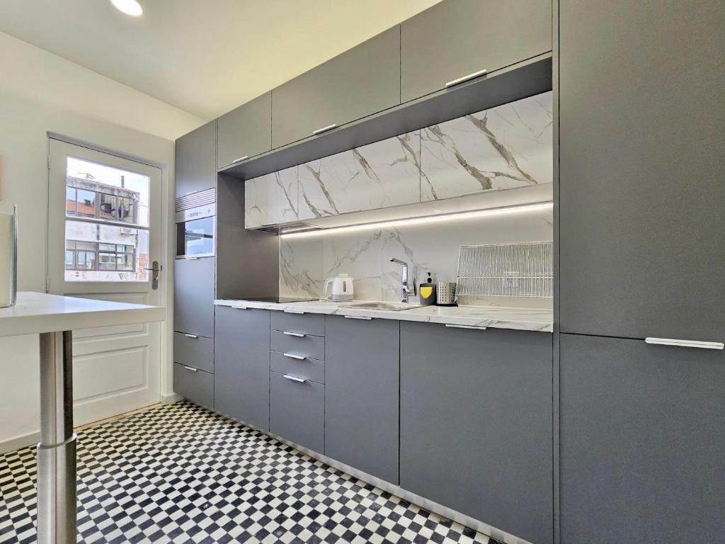 uma cozinha com armários cinzentos e piso em azulejo preto e branco em LM art apartments em Porto