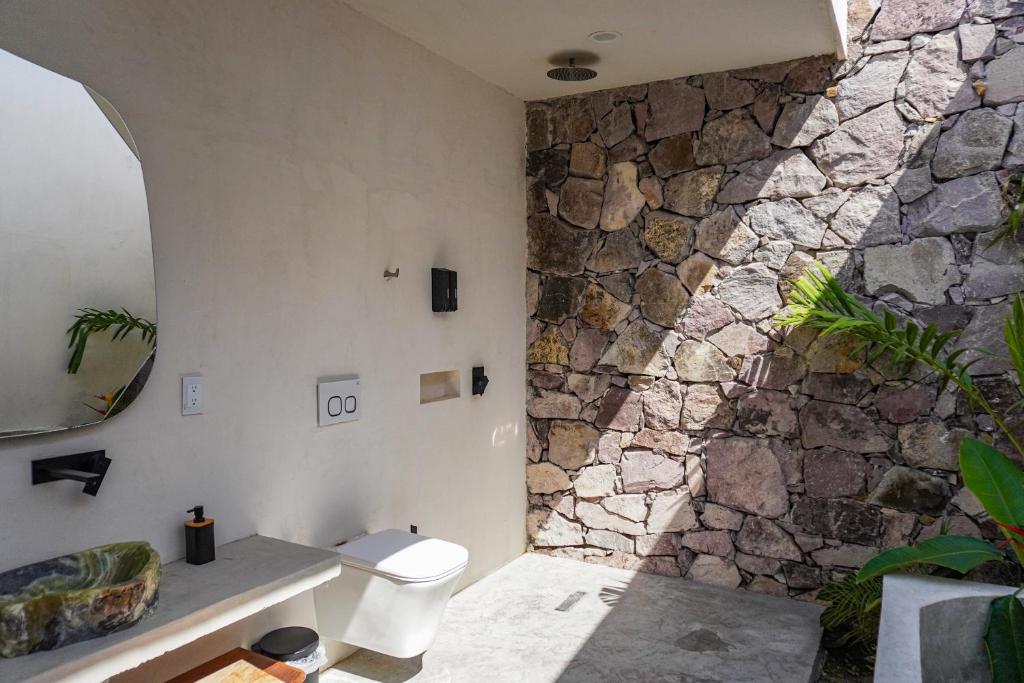 bagno con parete in pietra e servizi igienici. di Villa Quetzalpapalotl a Pérula