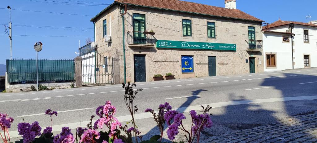 un edificio al lado de una calle con flores púrpuras en Donna Nega Alojamento Local, en Caminha