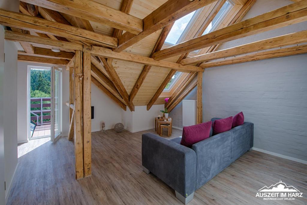 una sala de estar con sofá gris y techos de madera. en Auszeit im Harz - Haus 2 Wohnung 5, en Schierke