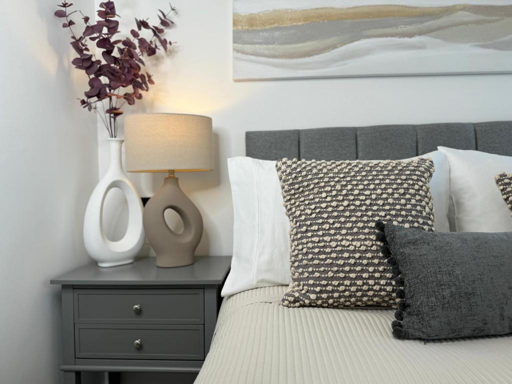 Modern One-Bedroom Apartment في سويندون: غرفة نوم مع سرير مع مزهرية على موقف ليلي