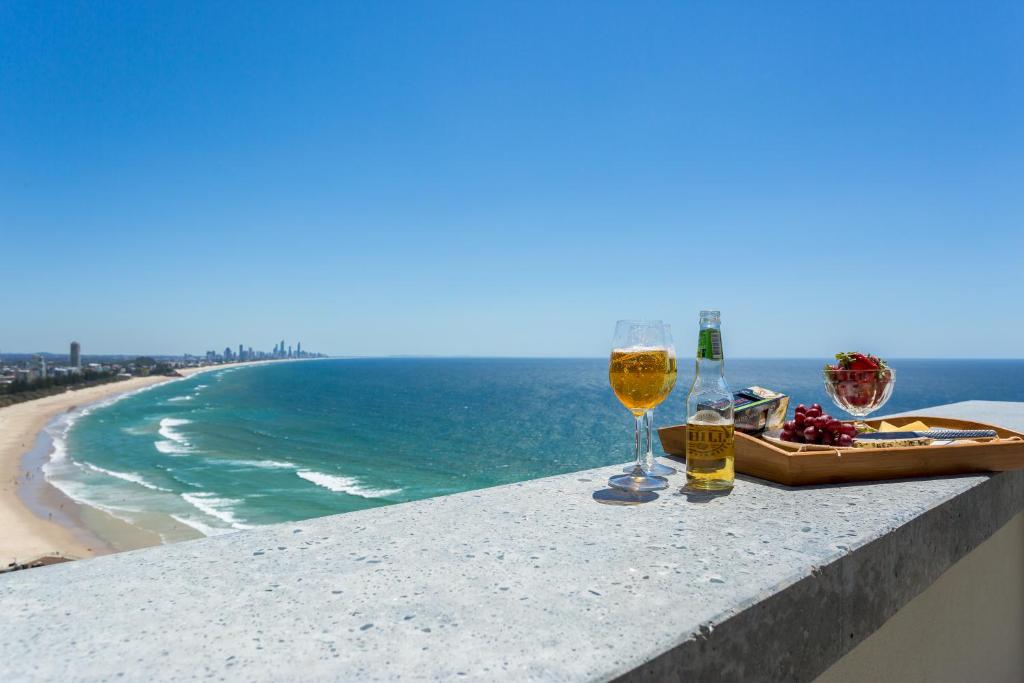 zwei Gläser Wein auf einem Vorsprung mit Blick auf den Strand in der Unterkunft Gemini Court Holiday Apartments in Gold Coast