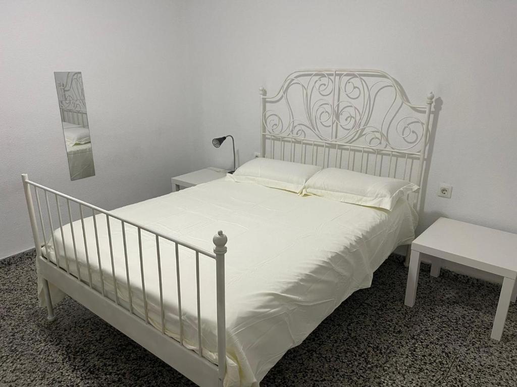 sypialnia z białym łóżkiem i stołem w obiekcie Apartamento de habitaciones privadas en el centro de Málaga w Maladze
