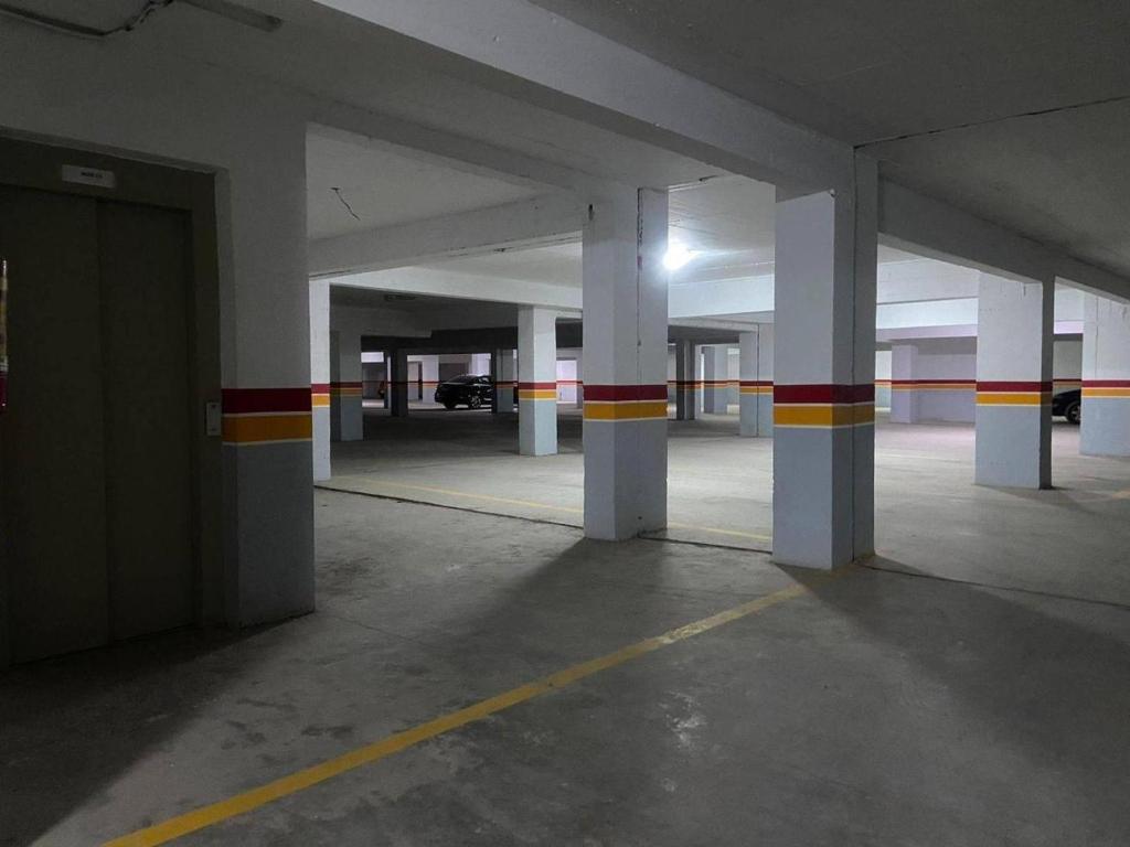 an empty parking garage with white columns and red and yellow stripes at Flat gueliz in Marrakesh