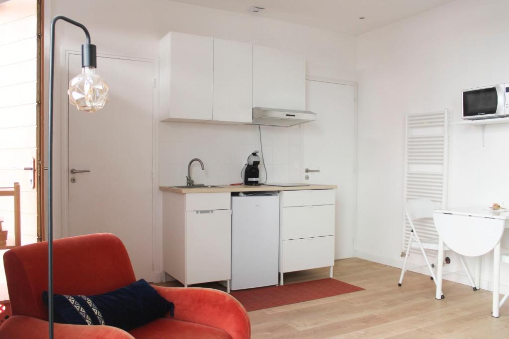 モントルイユにあるBeautiful renovated studio in dynamic neighborhoodのリビングルーム(赤い椅子付)、キッチン