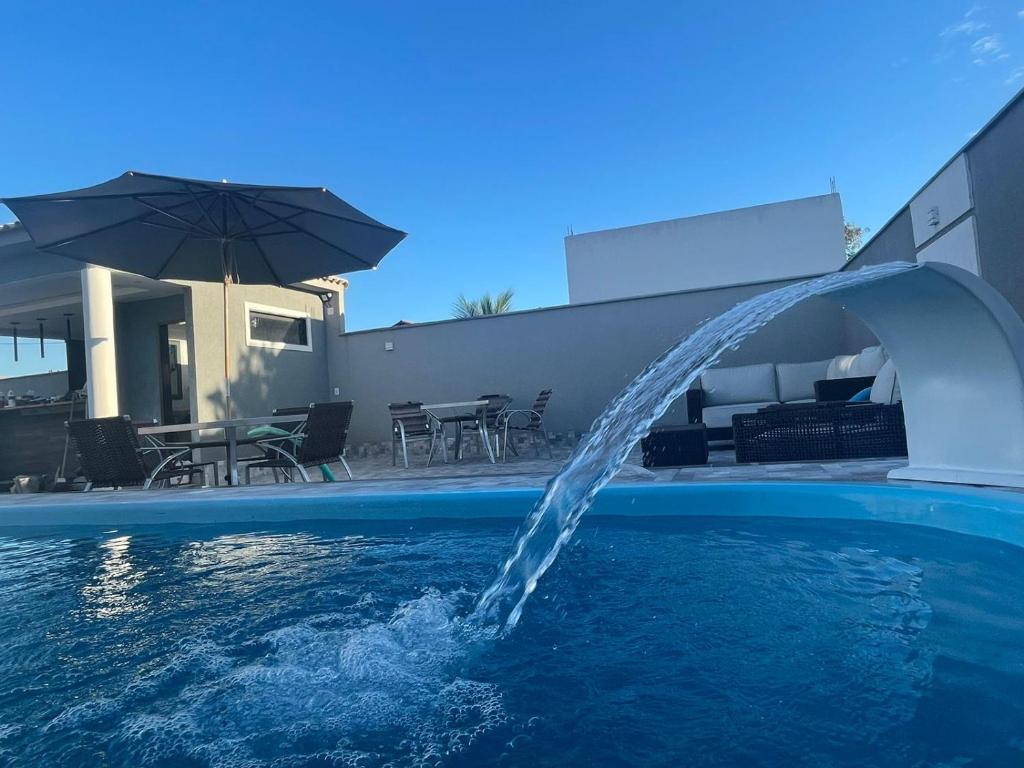 a water fountain in a swimming pool next to a house at A Casa in Maricá