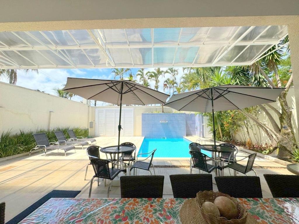 a patio with tables and umbrellas and a swimming pool at Pousada Village Cozumel in Guarujá