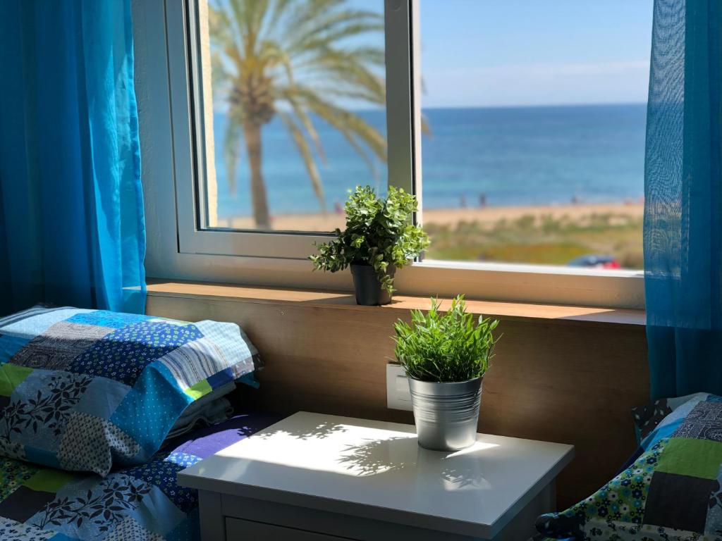 1 dormitorio con ventana y 2 macetas en una mesa en Cosy apartment directly on the beach / few mins from the city center, en Denia