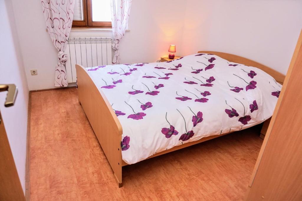 a bedroom with a bed with a floral bedspread at Apartment Stefica in Crveni Vrh