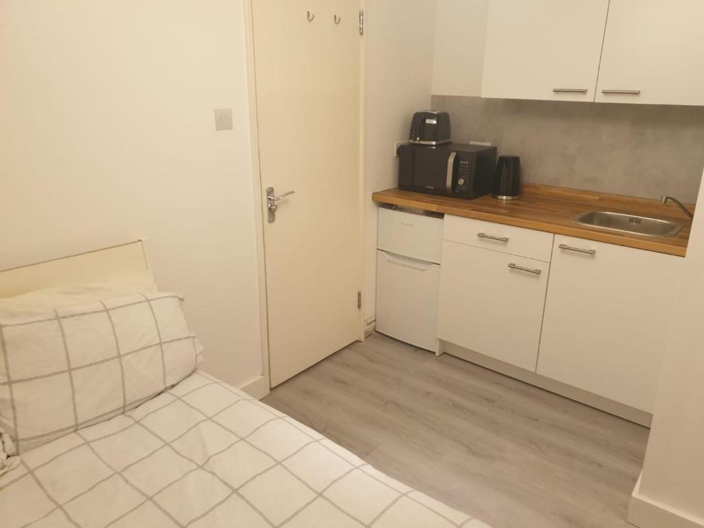 małą kuchnię ze zlewem i kuchenką mikrofalową w obiekcie Ensuite room w mieście Thamesmead