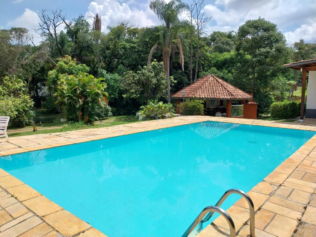 a blue swimming pool with a gazebo and trees at Chacara Recanto Paraíso Guacuri 2 in Itupeva
