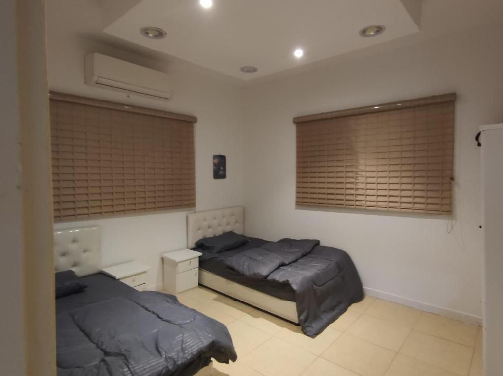 1 dormitorio con 2 camas y 2 ventanas en روز حي الربوه في الرياض en Riad